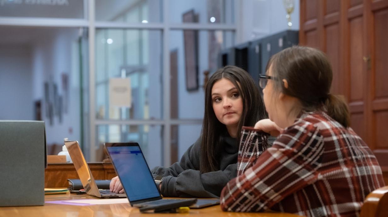 Two graduate students sitting at a table in the library.