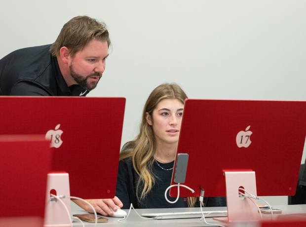 Instructor working with a student in a computer lab