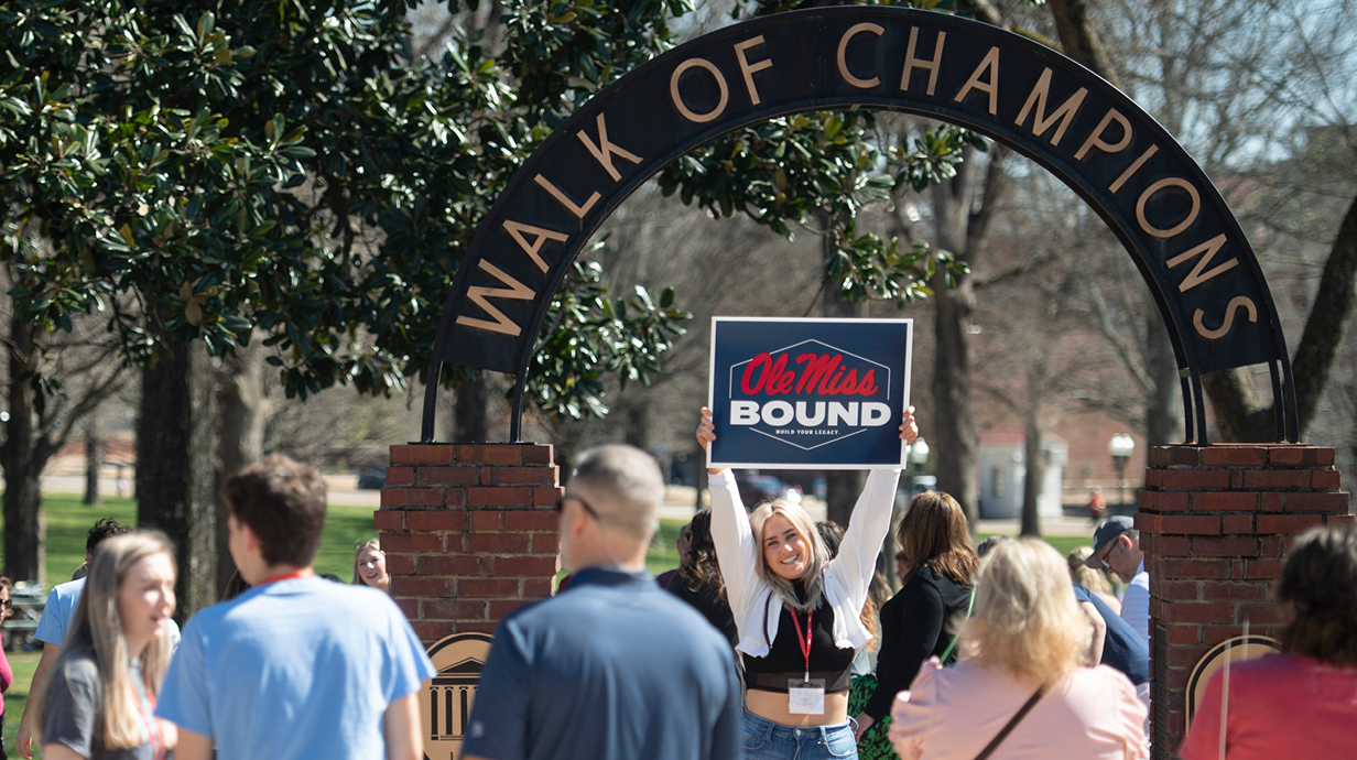 Incoming freshman holding Ole Miss bound sign in front of WOC on orientation day.