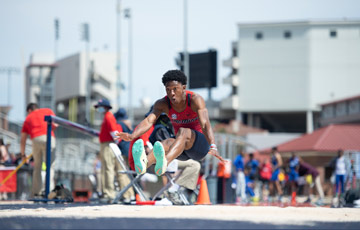 Track & Field student athlete doing the long jump into the sand pit.