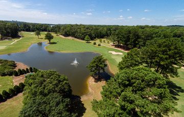 Aerial view of the Ole Miss Golf Complex. Lake with fountain, sand trap, and trees are focal points of photo. 