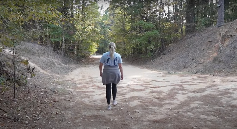 woman walking down a path through the forest