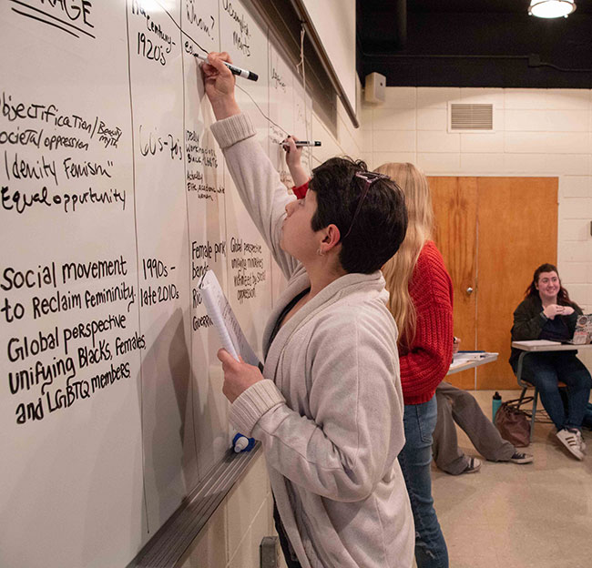 students writing notes on a whiteboard