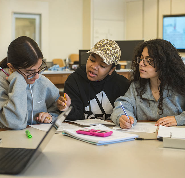 three female students work together and discuss biology