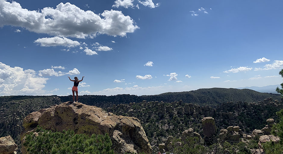 student stands on top of a hoodoo in the Arizona mountains