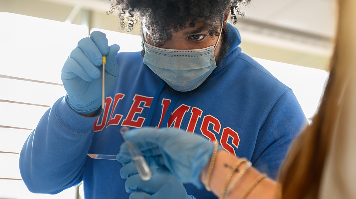 male student focused on adding a sample into a test tube