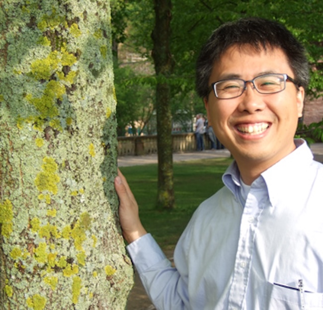 Erik Hom standing next to a tree covered in lichen