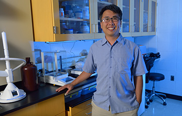 male professor standing in front of lab equipment