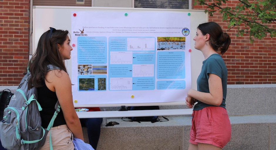 Two girls outside looking at a board with content on it.