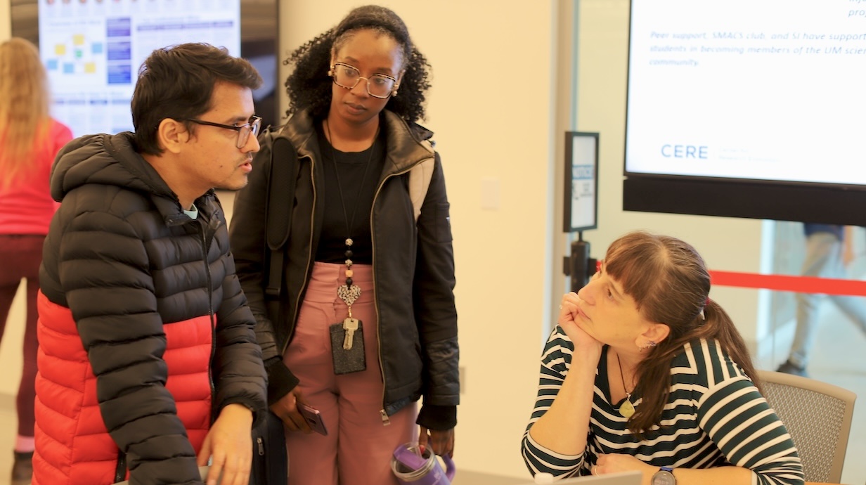 two students speaking with a professor