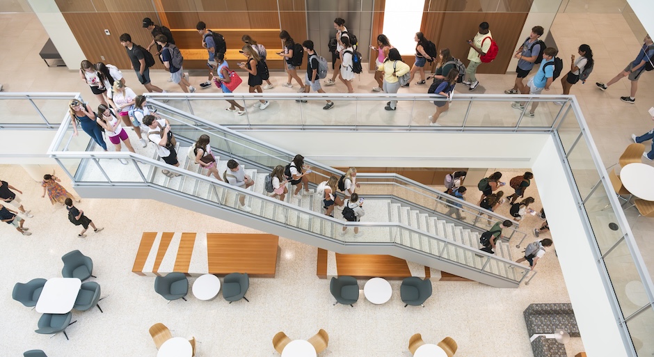 Inside photo taken from above of a staircase with students walking down it.