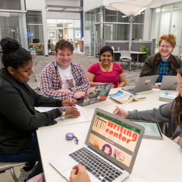 a small group of students seated at a table in the Writing Center