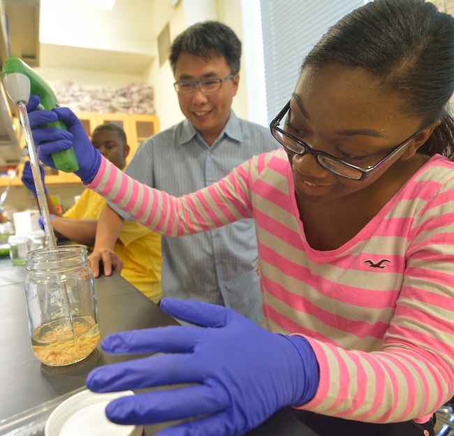 professor working with two highschool students in a lab