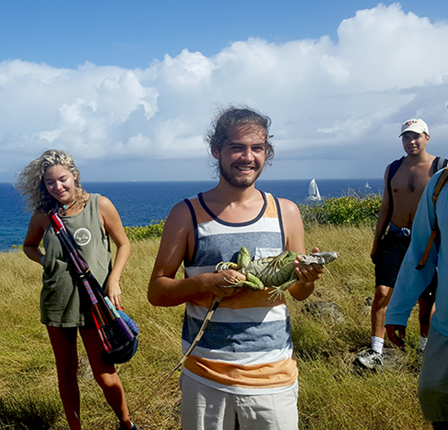 male student in the Caribbean holding an iguana.