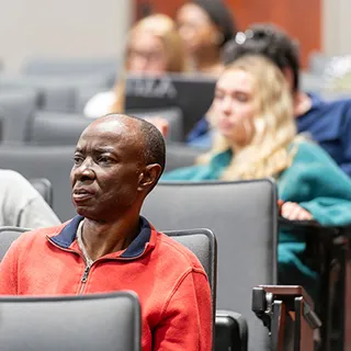 Audience members focus intently in auditorium.