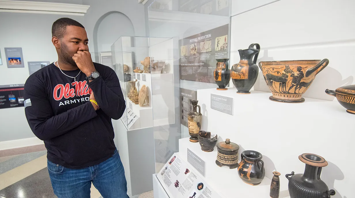 Student looks at Greek artifacts in museum