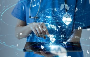 nurse holding a tablet and healthcare symbols floating in space in front of her