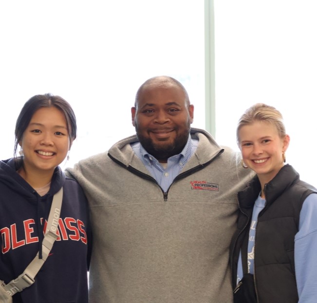 advisor standing with arms around two successful students accepted to dental school