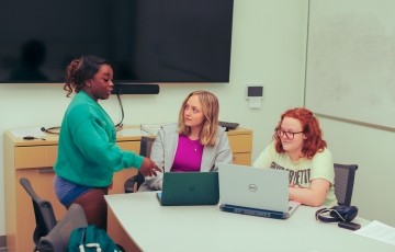 three students studying together in a room