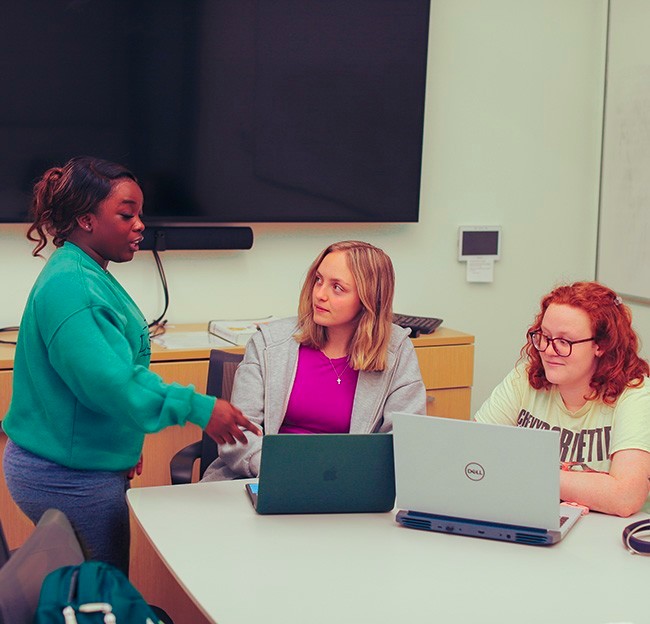 image of three students talking together in a study room.