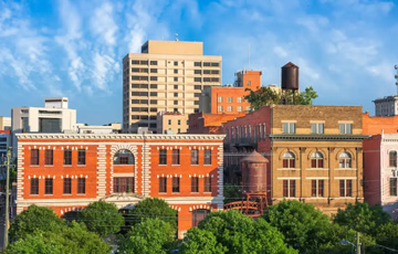 buildings with blue sky in the background and green tress in the foreground