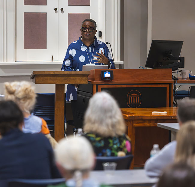 female speaker giving talk at podium in front of people