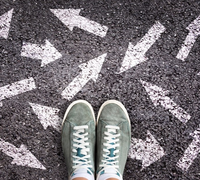 image of feet in sneakers with arrows drawn on the concrete pointing in different directions