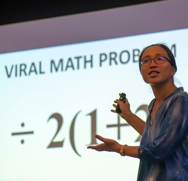 professor in front of projector screen teaching math