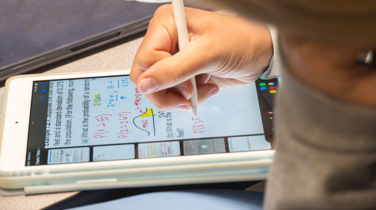 student writing math notes in a tablet