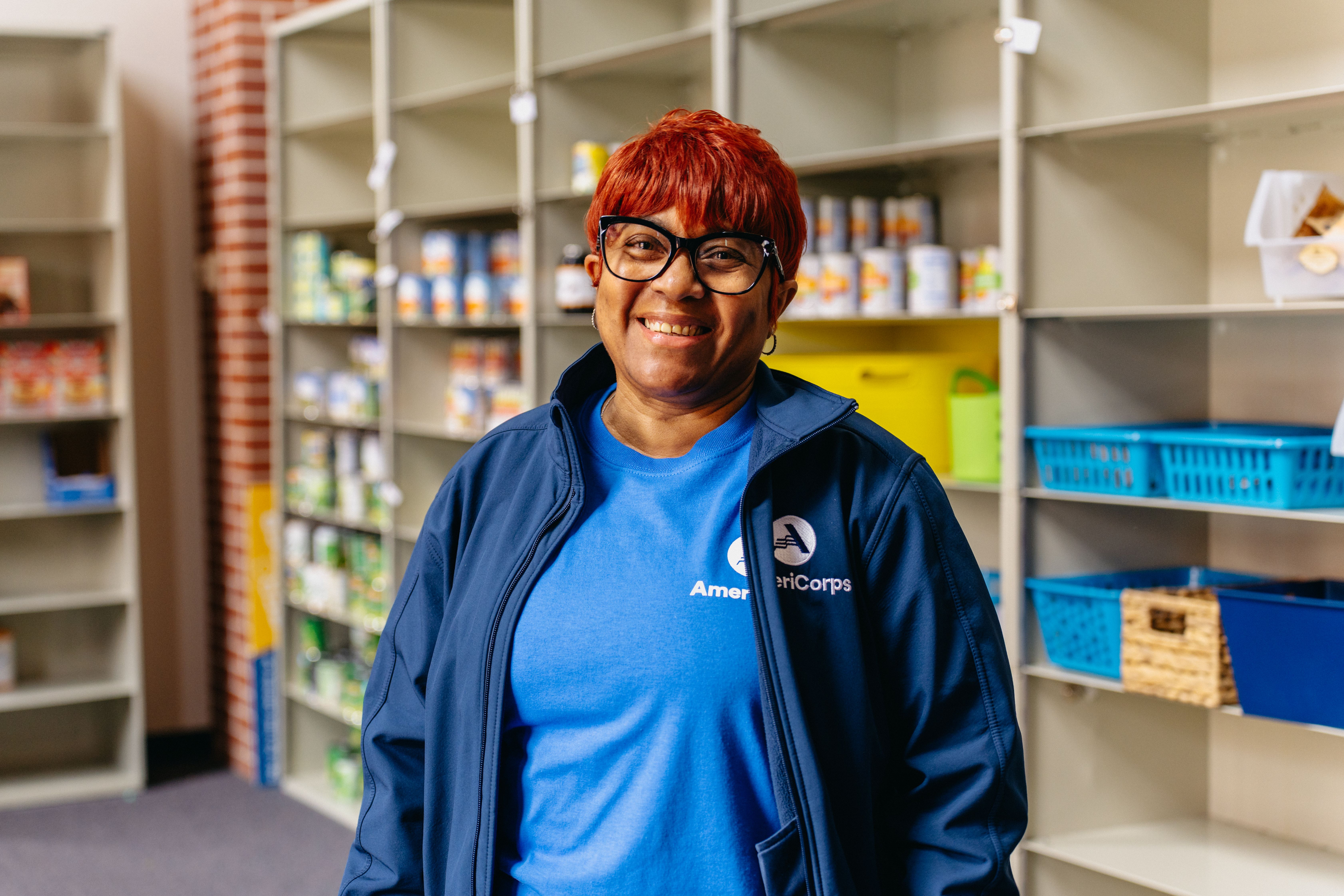 AmeriCorps Member, Jan, poses in Grove Grocery, surrounded by food