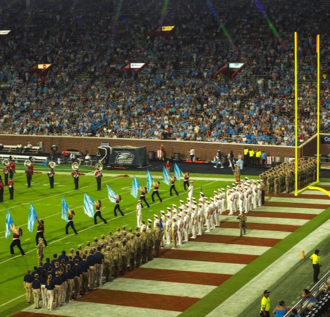 cadets from the different services lined up on sidelines of football stadium for military appreciation game