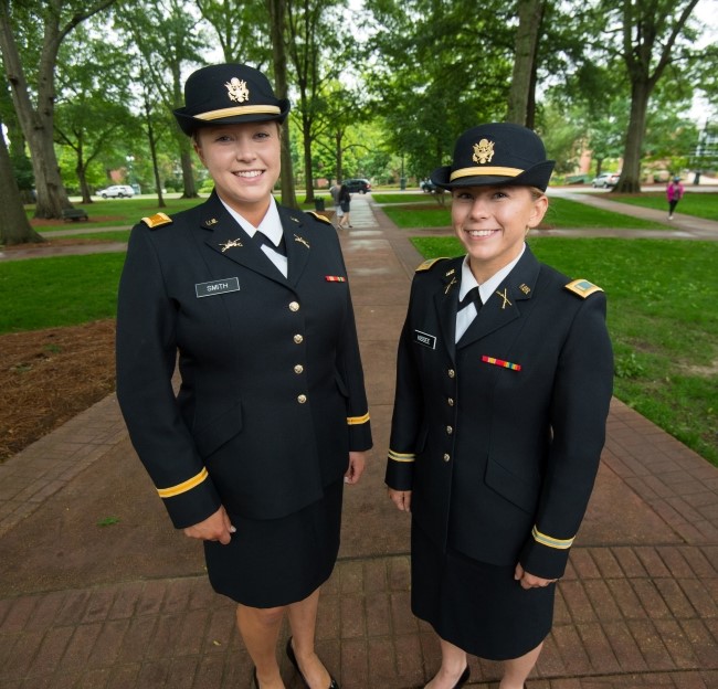 two female cadets in dress uniform standing together outside on campus