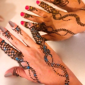 image of two women's hands with henna tattoos and designs