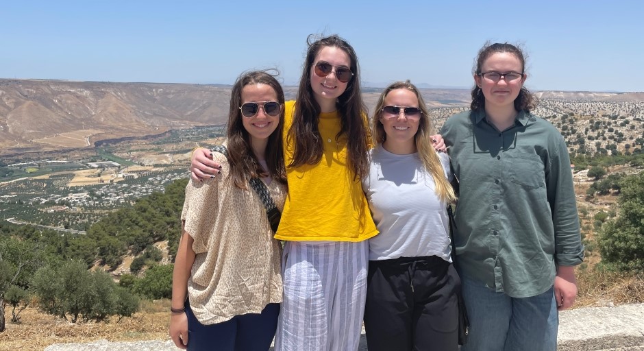 students standing together with a dry landscape that includes a valley and a small town in the background