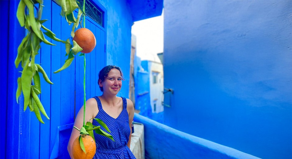 student standing in front of blue walls of a house in Morocco