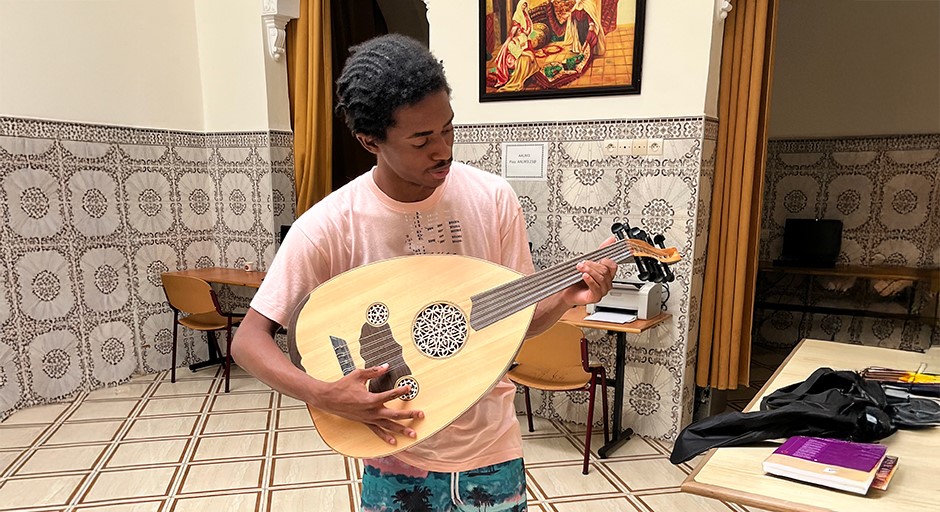 student holding and playing a traditional guitar 