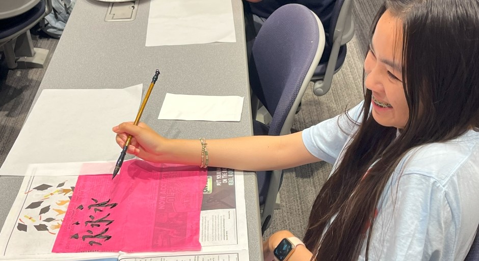 student seated at a desk working on calligraphy