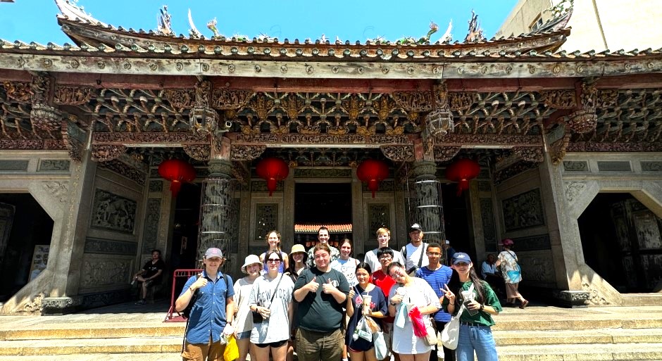 group of students standing in front of a traditional Chinese building