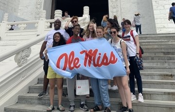 image of students standing on stairs holding a blue banner that says "Ole Miss"