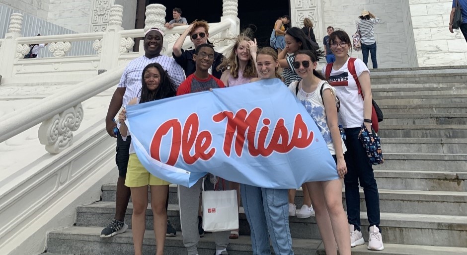 image of students standing on stairs holding Ole Miss banner