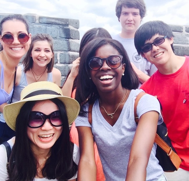 group of students and a professor smiling at a camera while standing on the Great Wall of China