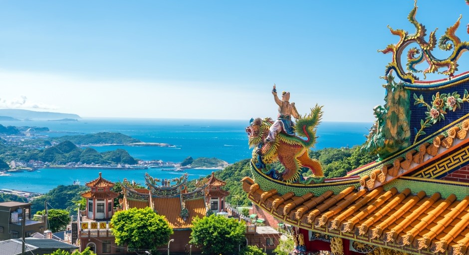 Chinese temple figures and decorations. in the background is the sea and mountains