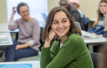 image of a student smiling in class as she looks at another student