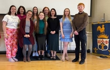 a small group of students standing together on a stage for a photograph at their honor society induction