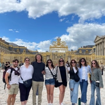 a group of students standing in front of gold colored elaborate gates