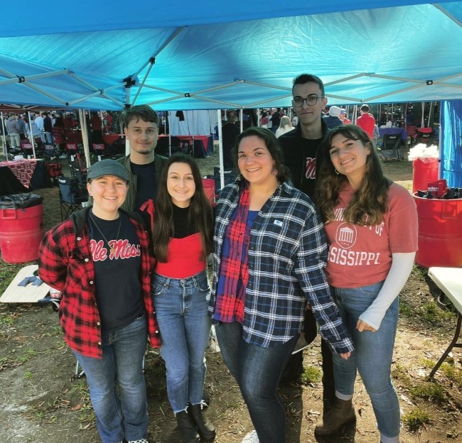 image of a small group of students standing under a tent during a football tailgate event