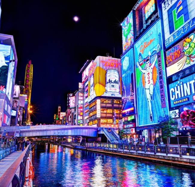 nighttime view of buildings lit up along a canal in Osaka