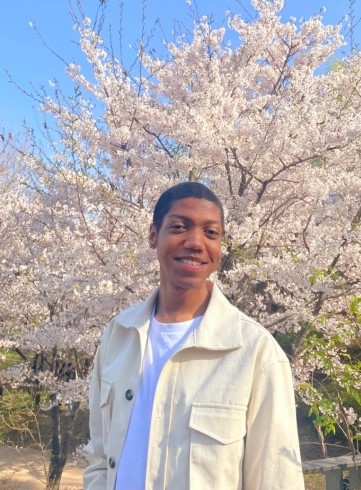 image of student standing in front of white blooms of a cherry tree