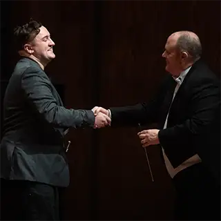 Band Director Tim Oliver shakes the hand of performer Philip Snyder