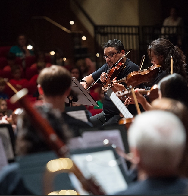 Members of the LOU Symphony Orchestra perform on stage in front of community members